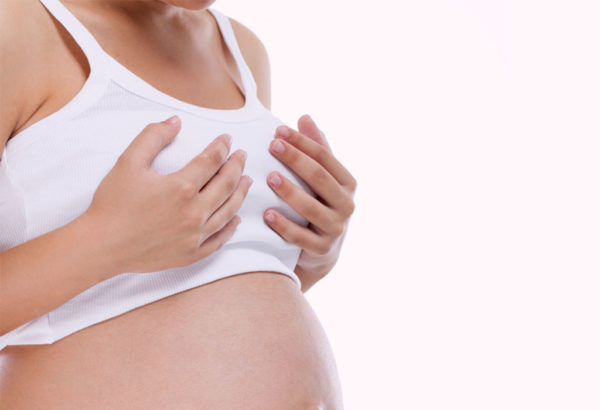 Беременная женщина держится за грудь